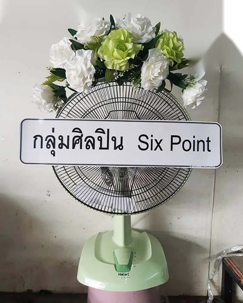 พวงหรีดพัดลมพร้อมป้ายชื่อกลุ่มผู้ส่งตั้งอยู่หน้าศาลา